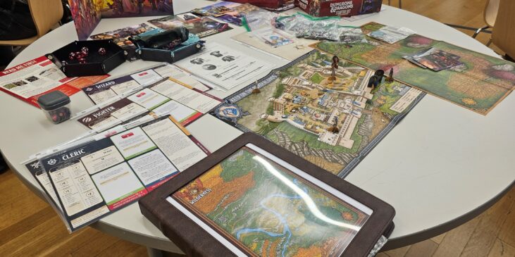 Mesa preparada para jugar Dungeons & Dragons, con dados, miniaturas, mapas, hojas de personaje y pantalla del director de juego.